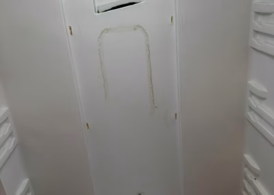 Panel trasero de un frigorífico con el desagüe del evaporador y la sonda a la vista durante el diagnóstico