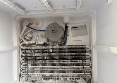 Evaporador de un frigorífico no-frost con escarcha acumulada, ventilador y resistencia de desescarche al descubierto