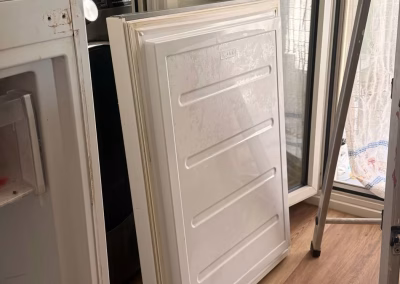 Puerta del congelador desmontada y apoyada en el suelo durante la reparación de un combi