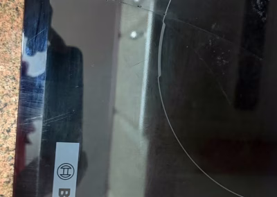 Vitrocerámica Bosch con el cristal agrietado, apoyada en la encimera durante la reparación