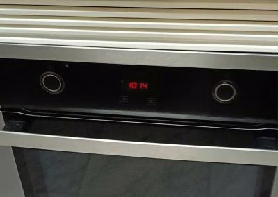 Horno empotrado de acero inoxidable con el display encendido tras la reparación, en una cocina de Palencia